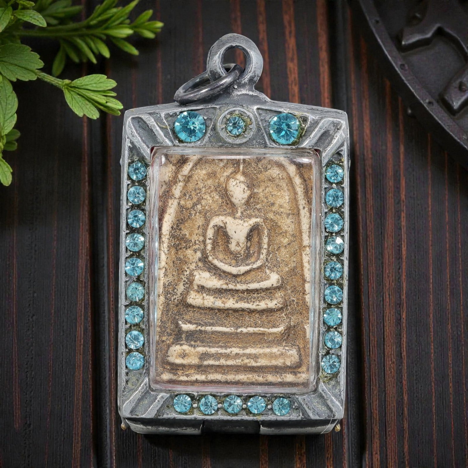 Thai Phra Somdej Amulet - Blue Crystal Silver Tone Pendant, 66ZB: A Thai Buddhist Phra Somdej amulet featuring a seated Buddha figure on tiered bases, housed in a silver-tone metal casing with vibrant blue crystal detailing. The glass-fronted enclosure protects the 