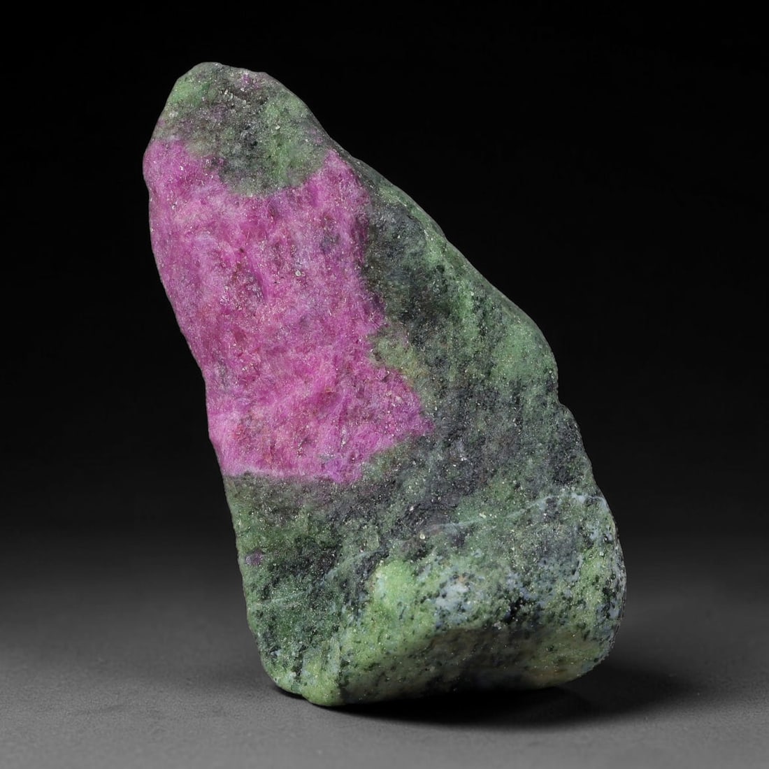 132ct Natural Tanzanian Ruby Zoisite Raw Rough Specimen Mineral Stone, 19YQ: This unpolished mineral rough is natural ruby zoisite sourced from Tanzania, exhibiting distinct banded mineral segregation of vibrant green zoisite, magenta ruby crystals, and dark hornblende inclusi