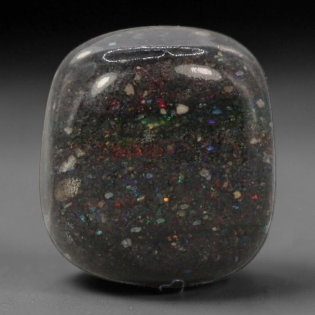 6.29 Carats Australian Matrix Opal Cushion Cabochon - Natural Stone, 75XB: This singular cushion cabochon matrix opal, measuring 12.6 x 11.3 x 6.1 mm, features a deep, dark host matrix studded with vibrant, scattered opal flecks. The polished surface reveals a dazzling play 