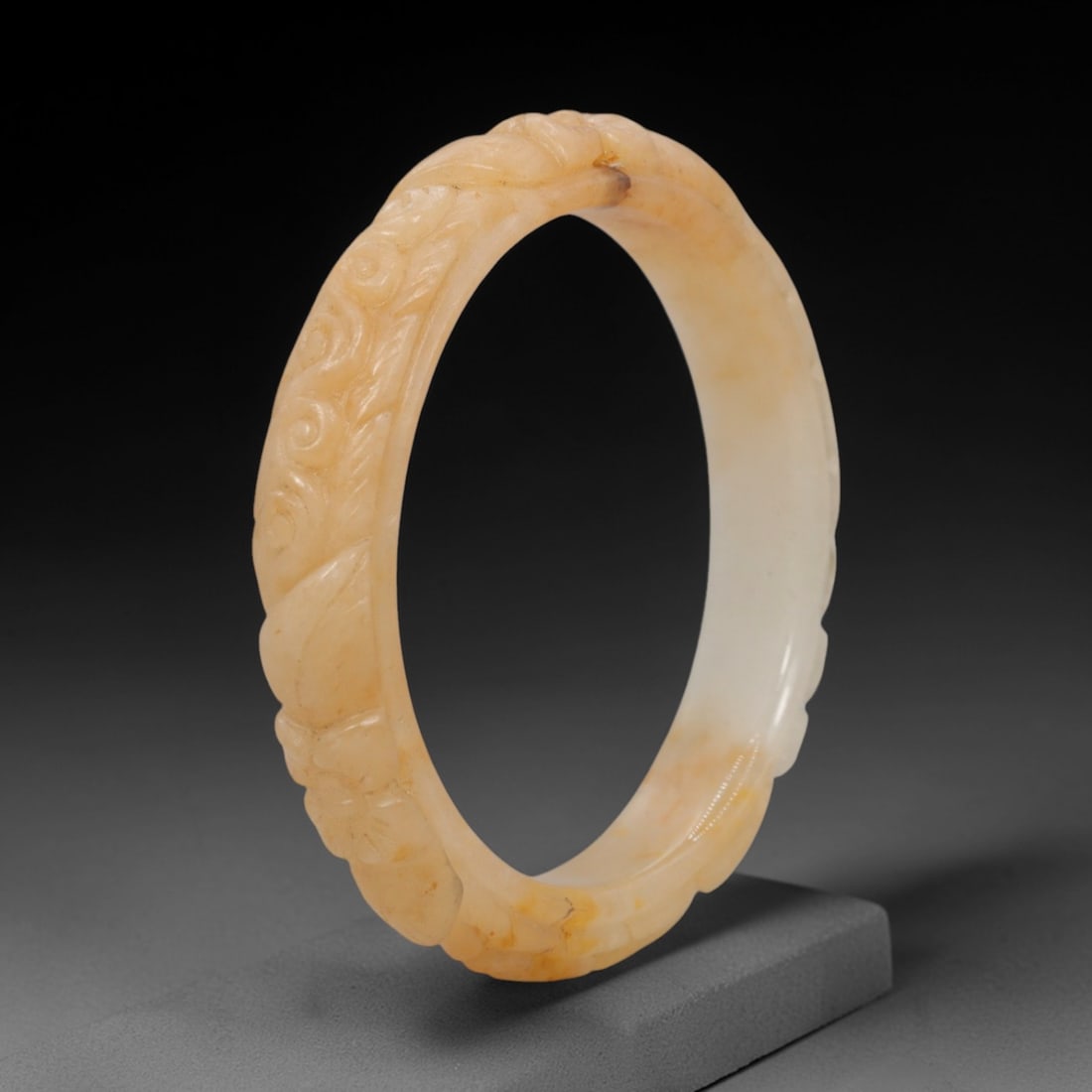 Natural Burmese Type A Carved Jadeite Jade Bangle Bracelet, 41ZL: A fine jadeite bangle of flattened circular form, masterfully carved in relief with a continuous band of scrolling foliate and floral motifs. The stone exhibits a captivating variegated palette, with 