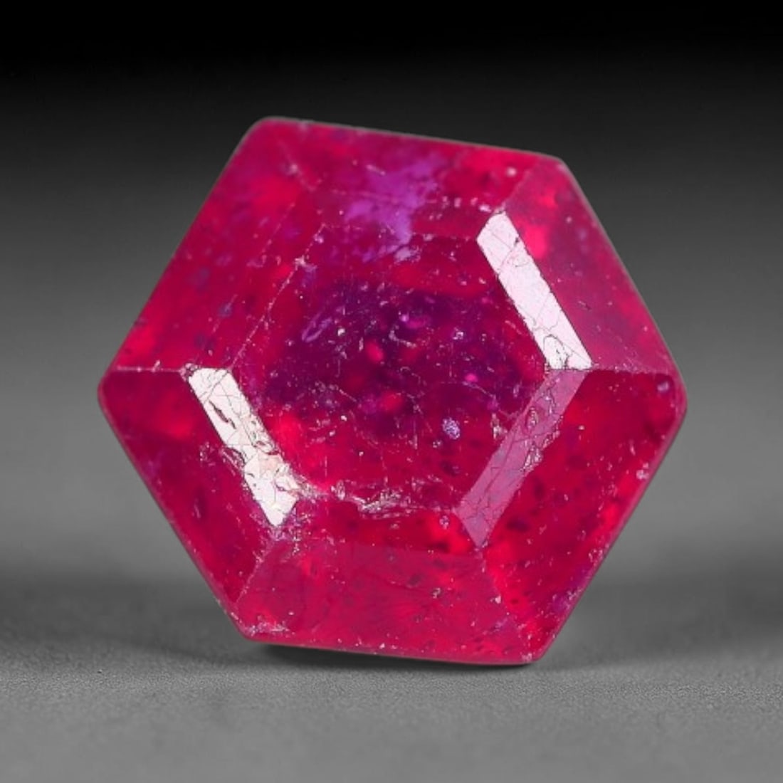 1.55 Carats Natural Madagascar Ruby Hexagon Cut Loose Gemstone, 74XM: This natural Madagascar ruby is cut into a geometric hexagon step faceted form, bearing a rich saturated crimson red hue characteristic of Malagasy corundum deposits. Natural internal fissures, scatte