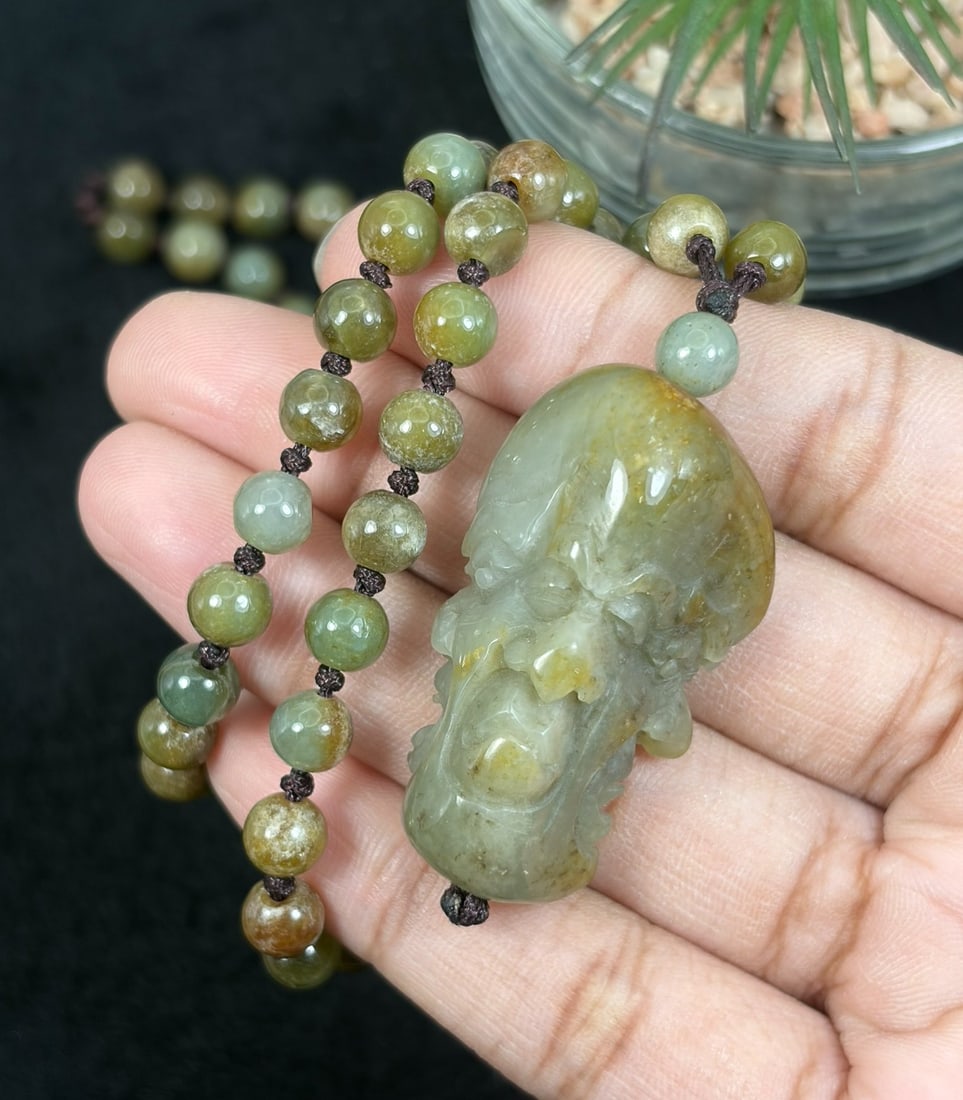 Burmese Jadeite Beaded Necklace with Hetian Jade Luohan Head Pendant, 97YJ: This necklace features a hand-carved Hetian jade luohan head pendant paired with natural Burmese jadeite round beads, strung on a brown cord. The pendant is crafted from Hetian jade with subtle natura