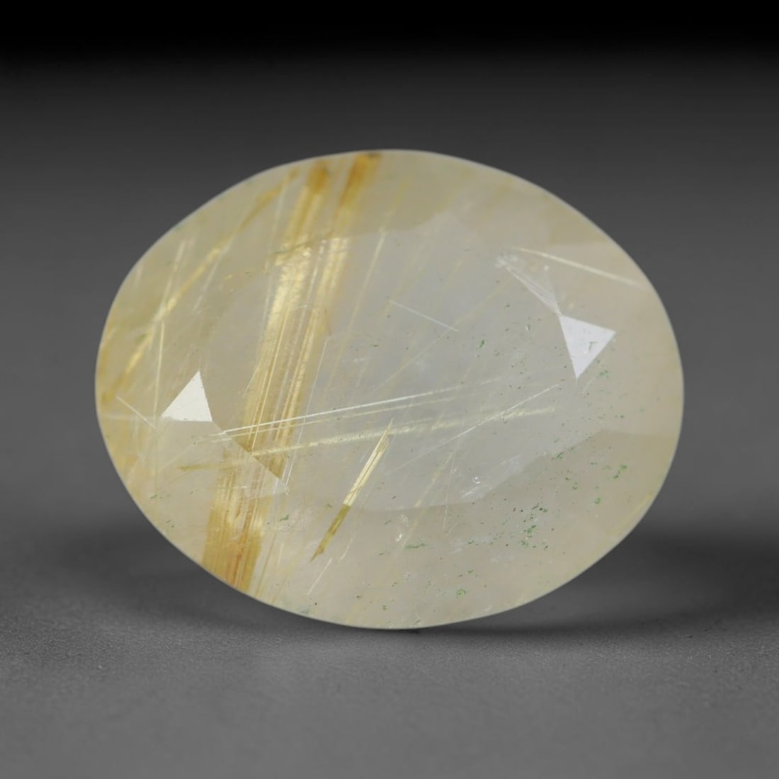 5.02 Carats Natural Golden Rutilated Quartz Oval Faceted Loose Gemstone, 18WS: This well-proportioned oval faceted rutilated quartz features a pale milky clear crystal base interspersed with striking dense golden needle rutile silk inclusions, paired with faint scattered green m