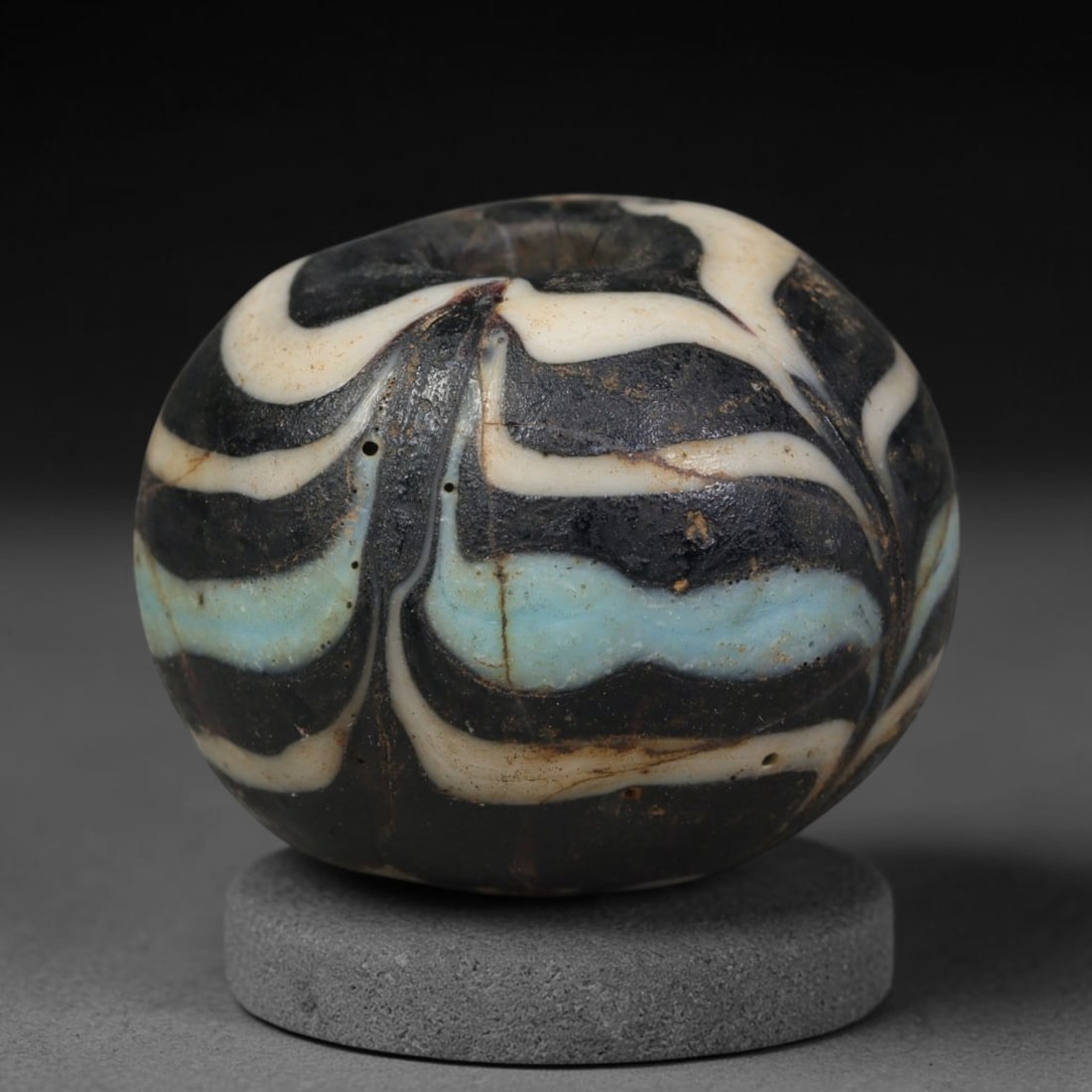 Ancient Islamic Hand Crafted Glass Bead Talisman, 22XD: Miniature antique wearable bead formed from hand-worked glass material, originating from ancient Islamic period glassmaking traditions across the Near East and North African cultural spheres. Glass wa