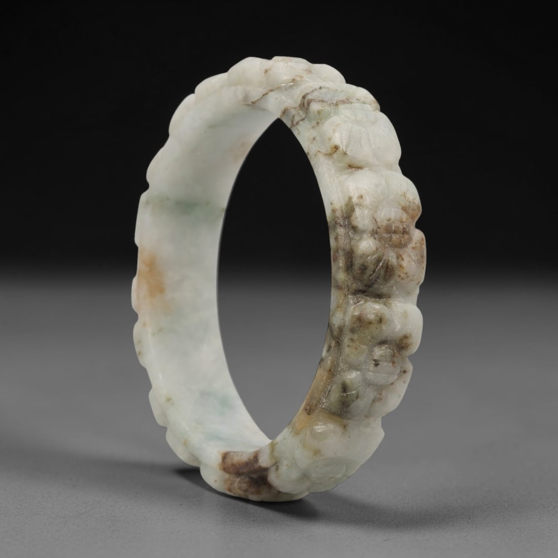 Natural Burmese Type A Carved Jadeite Jade Bangle Bracelet, 73ZL: A fine jadeite bangle of flattened circular form, masterfully carved in relief with a continuous band of chrysanthemum blossoms. The stone exhibits a striking variegated palette, with a pale milky-gre