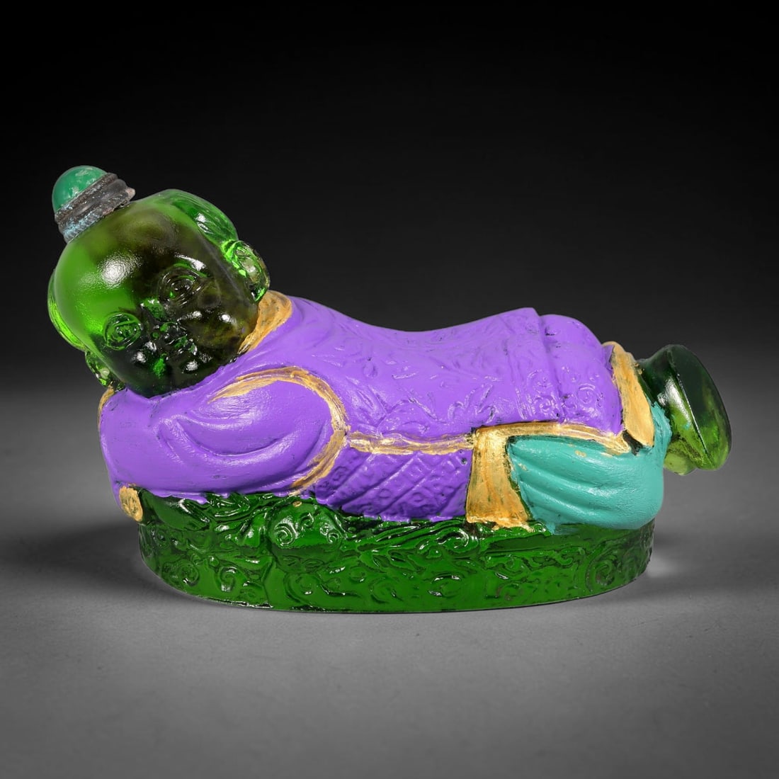 Vintage Chinese Liuli Glass Snuff Bottle - Reclining Sleeping Child, 62YF: This snuff bottle is moulded from translucent green liuli glass and shaped as a peacefully reclining sleeping child. The purple robe features fine embossed patterns highlighted with gilded trim, paire