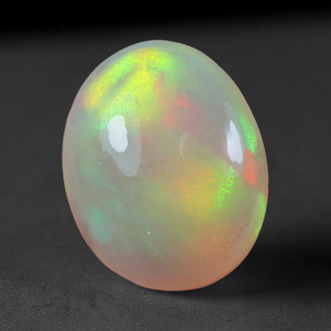 1.71 Carats Natural Ethiopian Welo Opal Oval Cabochon Loose Gemstone, 44XV: Natural Ethiopian Welo opal polished oval cabochon loose gemstone, luminous translucent milky white base stone with vivid multi-hued play-of-color featuring bright emerald green, lime yellow, soft blu