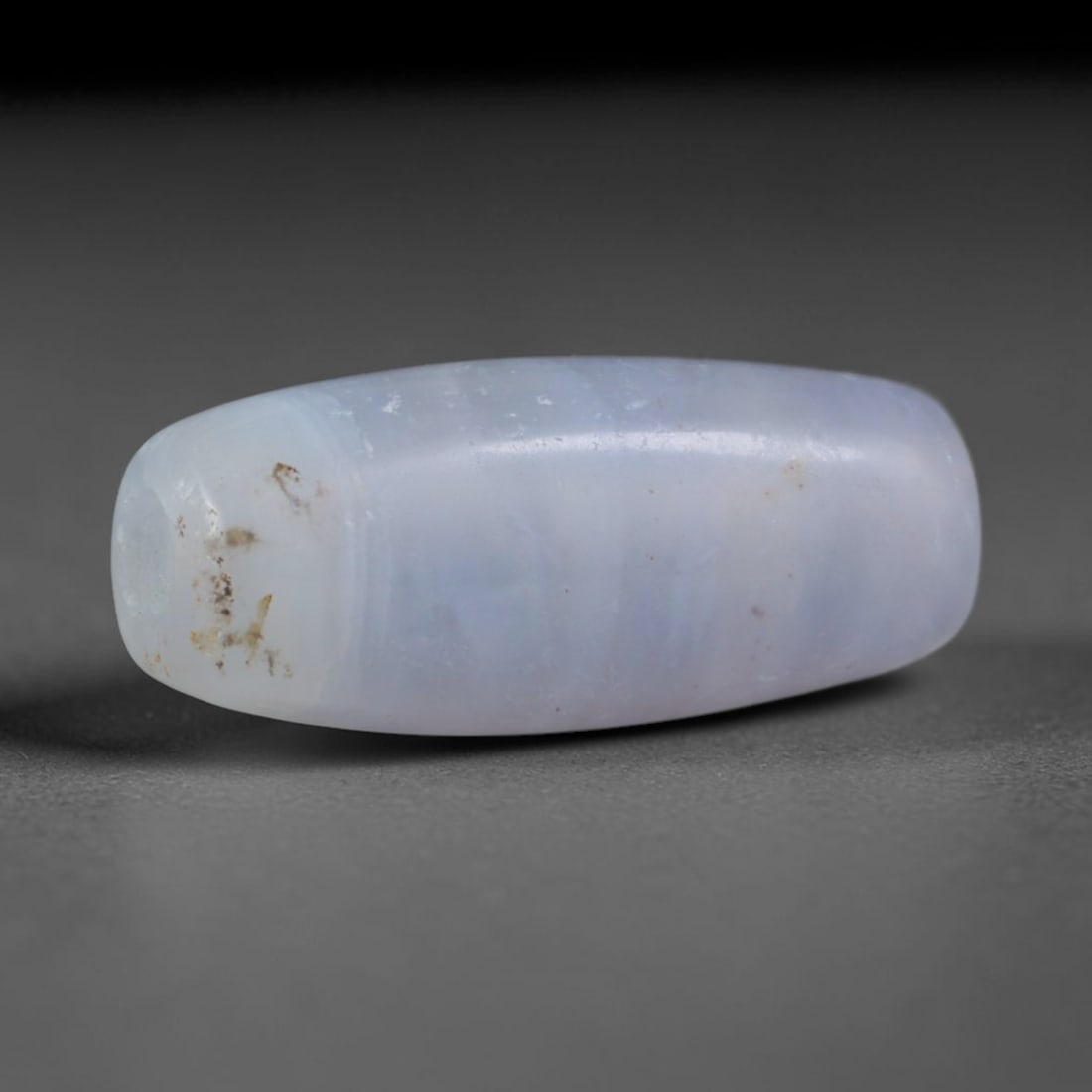Ancient Sogdian Pale Lavender Banded Chalcedony Slender Barrel Trade Bead (500-1000 CE), 32XD: This elongated slim barrel chalcedony bead was hand-fashioned by Sogdian Silk Road craftsmen, made as lightweight muted talismans favored by traveling merchants for delicate stacked necklaces. The tra