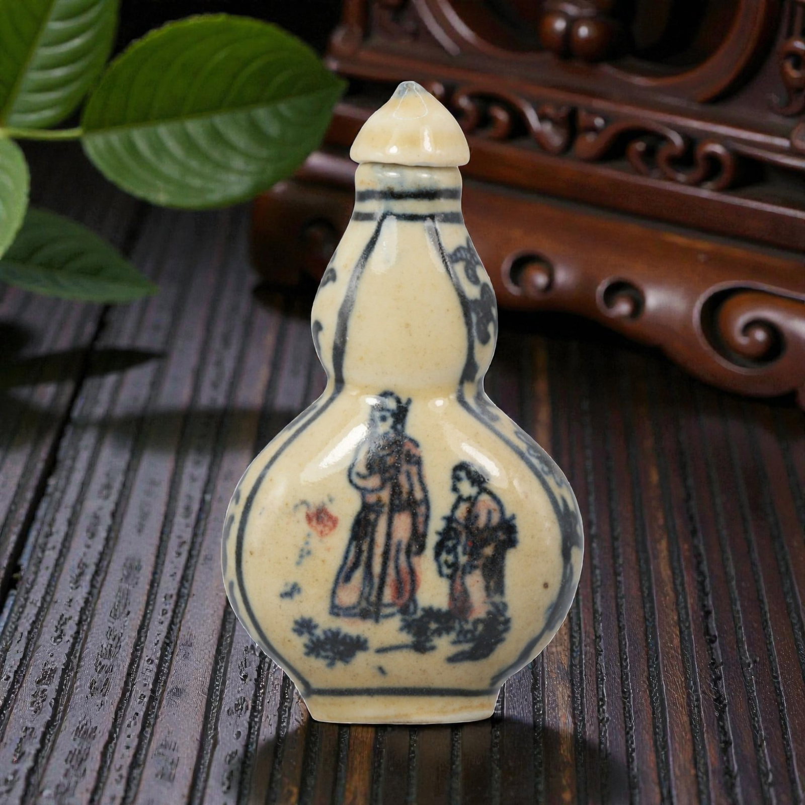 A Chinese Porcelain Double-Gourd Snuff Bottle, 20th Century, 4YD: Crafted from porcelain with a pale cream glaze and decorated in underglaze blue with copper red accents, the snuff bottle is formed in a double-gourd shape, with a narrow upper bulb, a wider lower bul