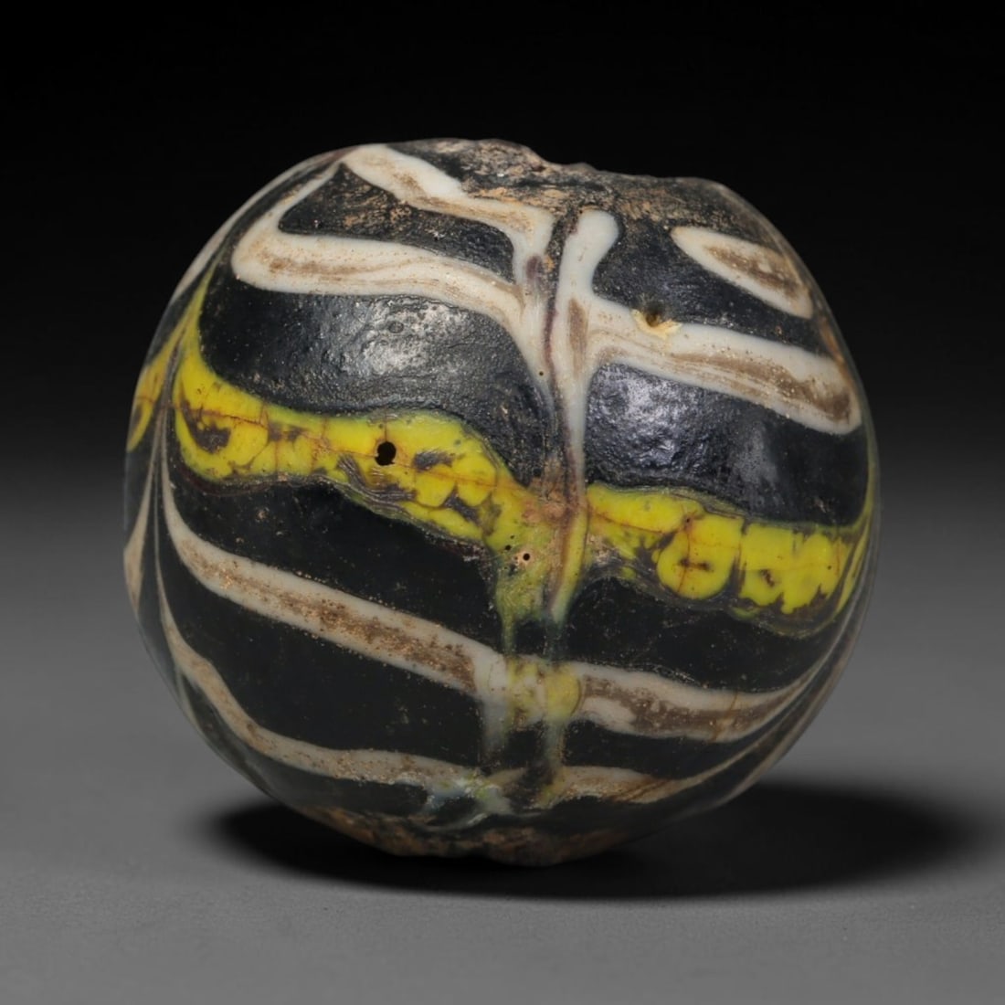Ancient Islamic Hand Crafted Glass Bead Talisman, 23XD: Miniature antique wearable bead formed from hand-worked glass material, originating from ancient Islamic period glassmaking traditions across the Near East and North African cultural spheres. Glass wa
