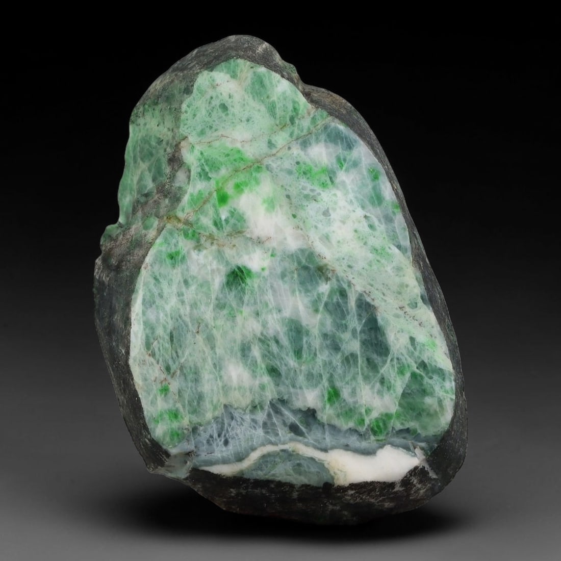 275ct Natural Type A Burmese Jadeite Jade Sliced Rough, 14YK: This specimen is a sliced rough block of natural Type A Burmese jadeite jade. The interior displays natural colour zoning with visible mineral veining and crystalline patterns typical of unprocessed j