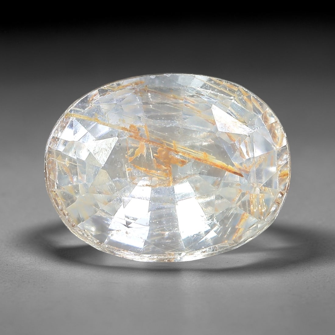1.02ct Natural Unheated White Sapphire Oval Loose Gemstone, LZ537: This natural oval faceted white sapphire weighs 1.02 carats with precise dimensions of 6.8x5.2x3.2mm. It features a transparent colorless base tone, filled with prominent golden rutile needle silk inc