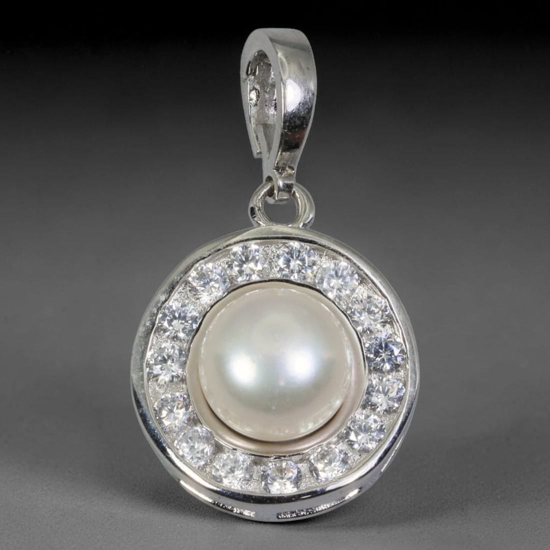 Round Halo Freshwater Pearl Clip-On Pendant with Cubic Zirconia Border, 99WP: Luxury silver-toned clip bail pendant with overall dimensions 22.6x18.9x9.2mm. At its center sits a smooth, high-luster creamy white freshwater pearl with soft iridescent overtones, securely set withi