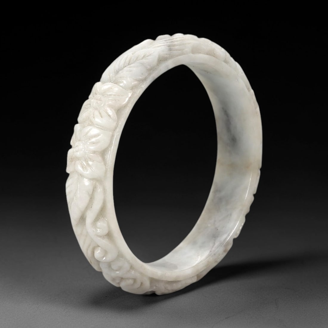 Natural Burmese Type A Carved Jadeite Jade Bangle Bracelet, 58ZL: A fine jadeite bangle of flattened circular form, masterfully carved in relief with a continuous band of floral blossoms and scrolling foliate motifs. The stone exhibits a translucent pale white base,