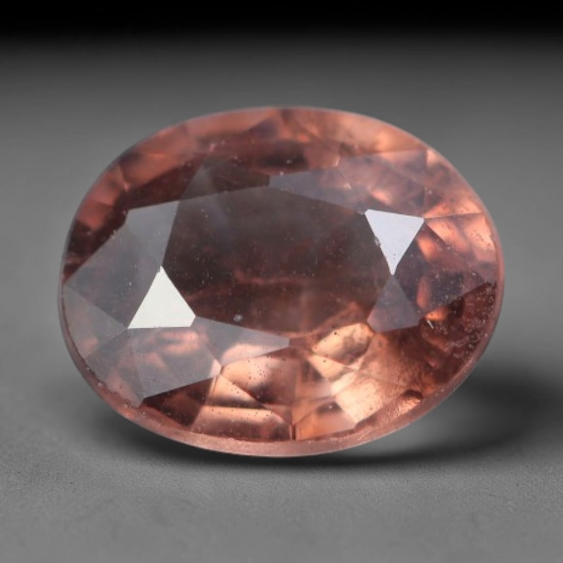 0.39 Carats Natural Pink Peach Sapphire Oval Faceted Loose Gemstone, 76XV: Natural warm pink-peach corundum sapphire precision cut into an oval faceted loose gemstone, fashioned with mixed brilliant facets to amplify warm color reflection. The crystal holds a soft muted pink