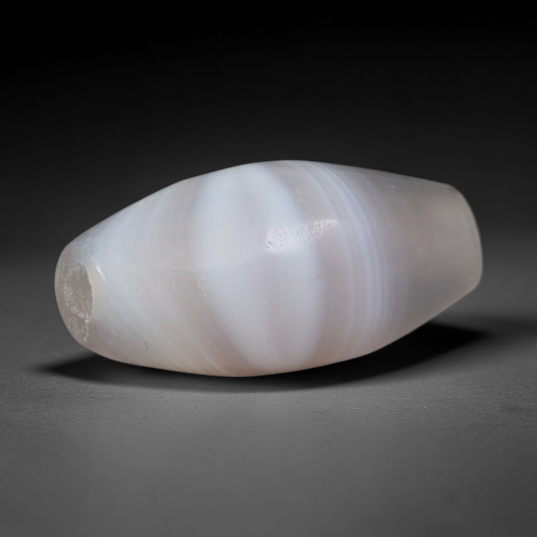 Ancient Greco-Bactrian Pale Banded Agate Miniature Bicone Trade Bead (250 BCE - 125 BCE), 43XD: This tiny antique pale banded agate bicone bead originates from Greco-Bactrian Central Asian artisan workshops, creators of delicate miniature chalcedony talismans ideal for layered necklaces and smal