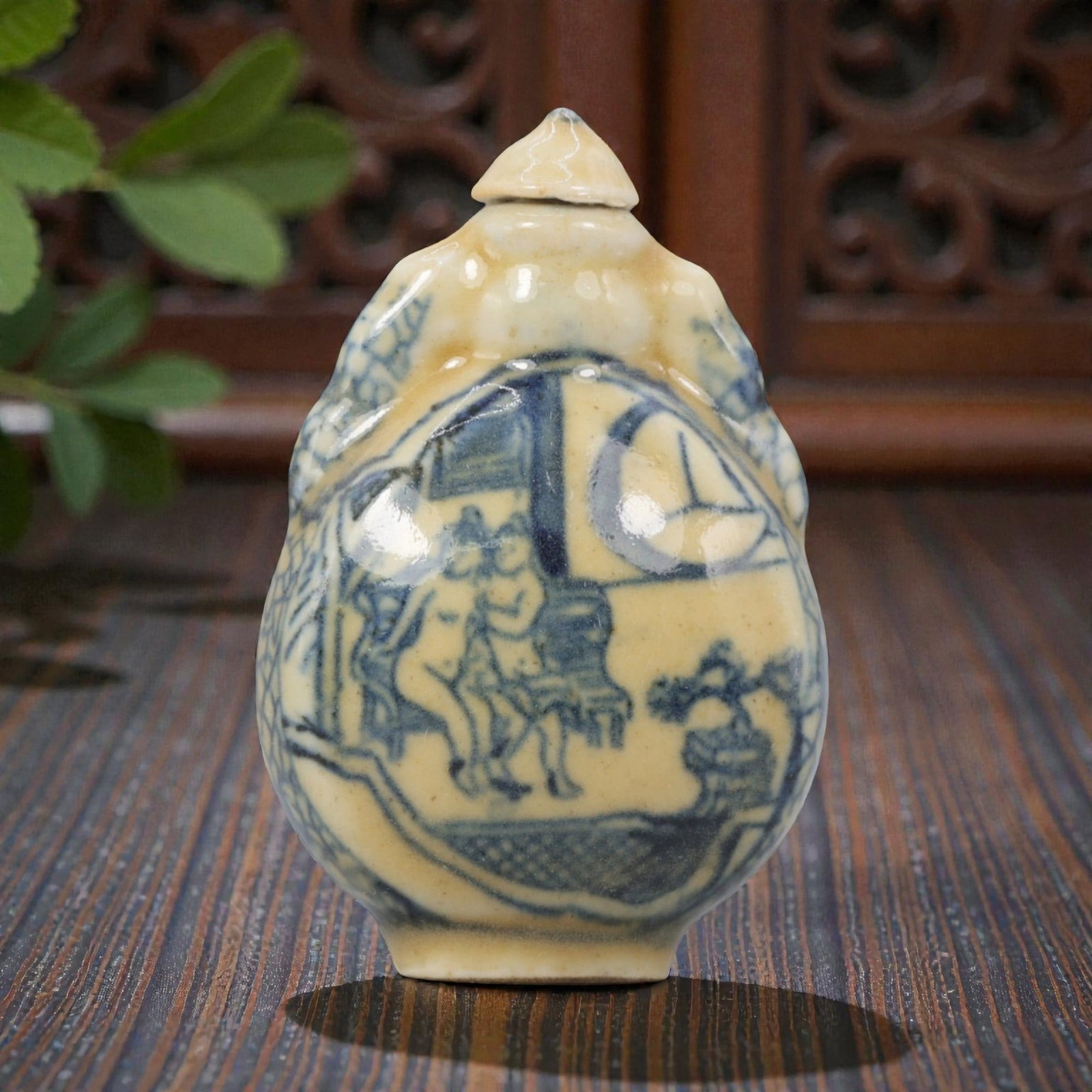 A Chinese Porcelain Snuff Bottle, 20th Century, 8YD: Crafted from porcelain with a pale cream glaze and decorated in underglaze blue, the snuff bottle features a rounded body with molded figural handles to either side, a short cylindrical neck, and a co
