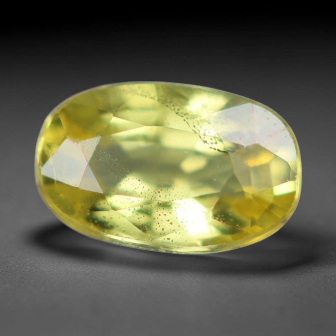 0.30 Carats Natural Yellow Sapphire Oval Faceted Loose Gemstone, 84XV: Natural golden yellow corundum sapphire precision fashioned as an oval faceted loose gemstone, cut with mixed brilliant facets to amplify light refraction. The stone carries a soft lemon-yellow hue wi