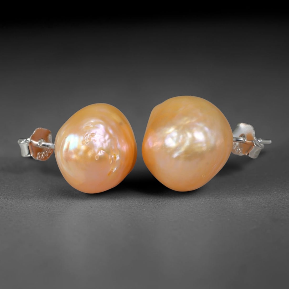 Natural Baroque Warm Apricot Peach Pearl Stud Earrings, 44WE: Matched minimalist stud earrings featuring organic asymmetrical baroque freshwater pearls, each measuring 13.5x9.9mm. The pearls boast thick, glossy nacre with rich warm apricot-peach primary tones, a