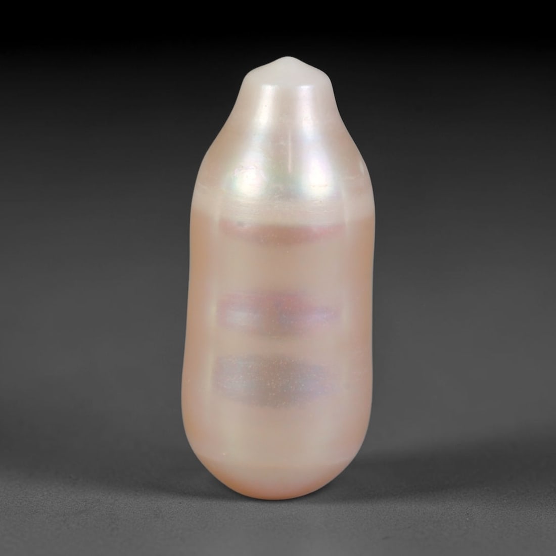 Natural Freshwater Baroque Pearl - Pale Blush Champagne Elongated Form, 66WE: This natural freshwater baroque pearl boasts an elongated organic silhouette enveloped in smooth, glossy iridescent nacre, featuring pale blush pink and soft champagne shifting overtones across its po