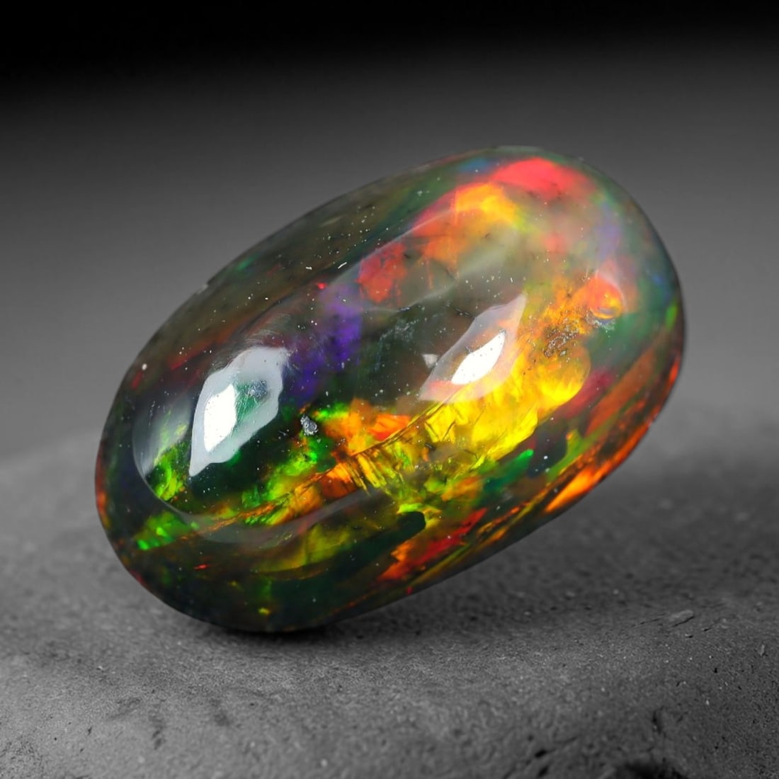 2.23ct Natural Ethiopian Welo Black Smoked Opal Cabochon Loose Gemstone, 96WP: This fully polished Ethiopian Welo opal features a dark smoked base with vivid, sweeping play-of-color shifting across its glossy dome surface, measured at 11.7x7.4x5.2mm. The black smoke treatment de