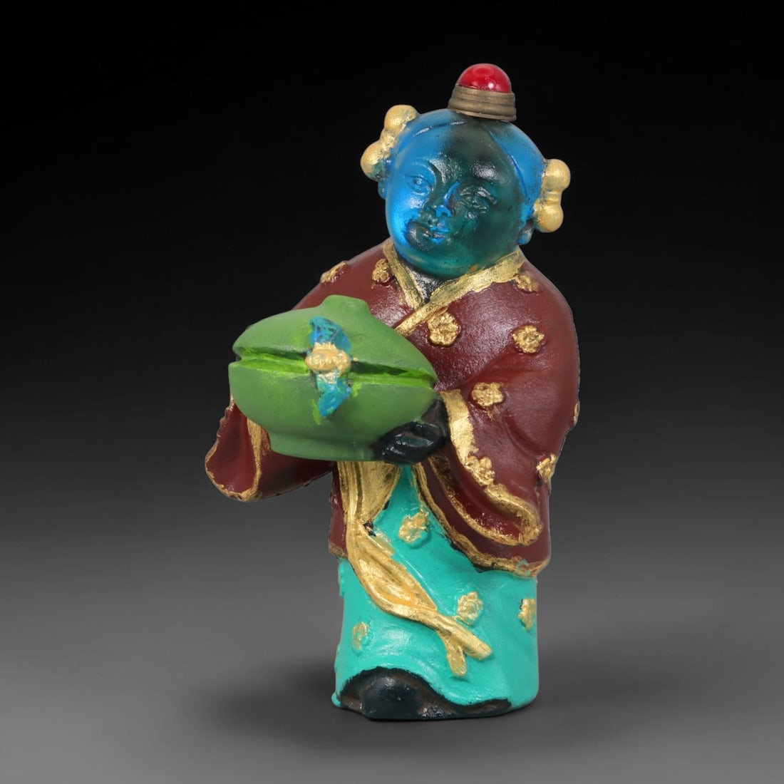 Vintage Chinese Liuli Glass Snuff Bottle - Girl Holding Treasure Censer, 69YF: This snuff bottle is cast from translucent blue liuli glass forming the head, sculpted as a young girl with double hair buns holding a green covered censer with gilded ornament. Her traditional red up