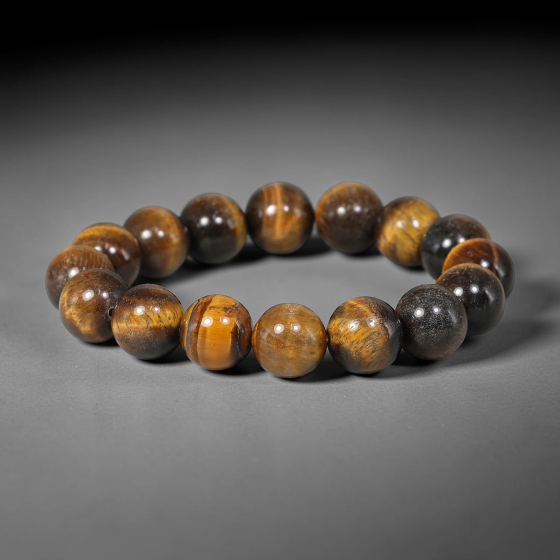 Tiger Eye Bead Bracelet - Polished Natural Stone Jewelry, 58YM: A bracelet composed of polished tiger's eye beads, exhibiting a rich chatoyant banding in golden brown, deep brown, and near-black tones. The beads are generally spherical with minor natural variation
