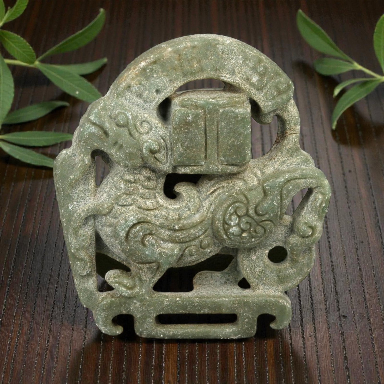 A Chinese Hardstone Openwork Belt Plaque with Mythical Beast, 20th Century, 30YB: Carved from mottled greenish-grey hardstone with granular texture and natural inclusions, the plaque is worked in openwork relief depicting a stylized mythical beast, likely a bixie or chi-dragon, sho