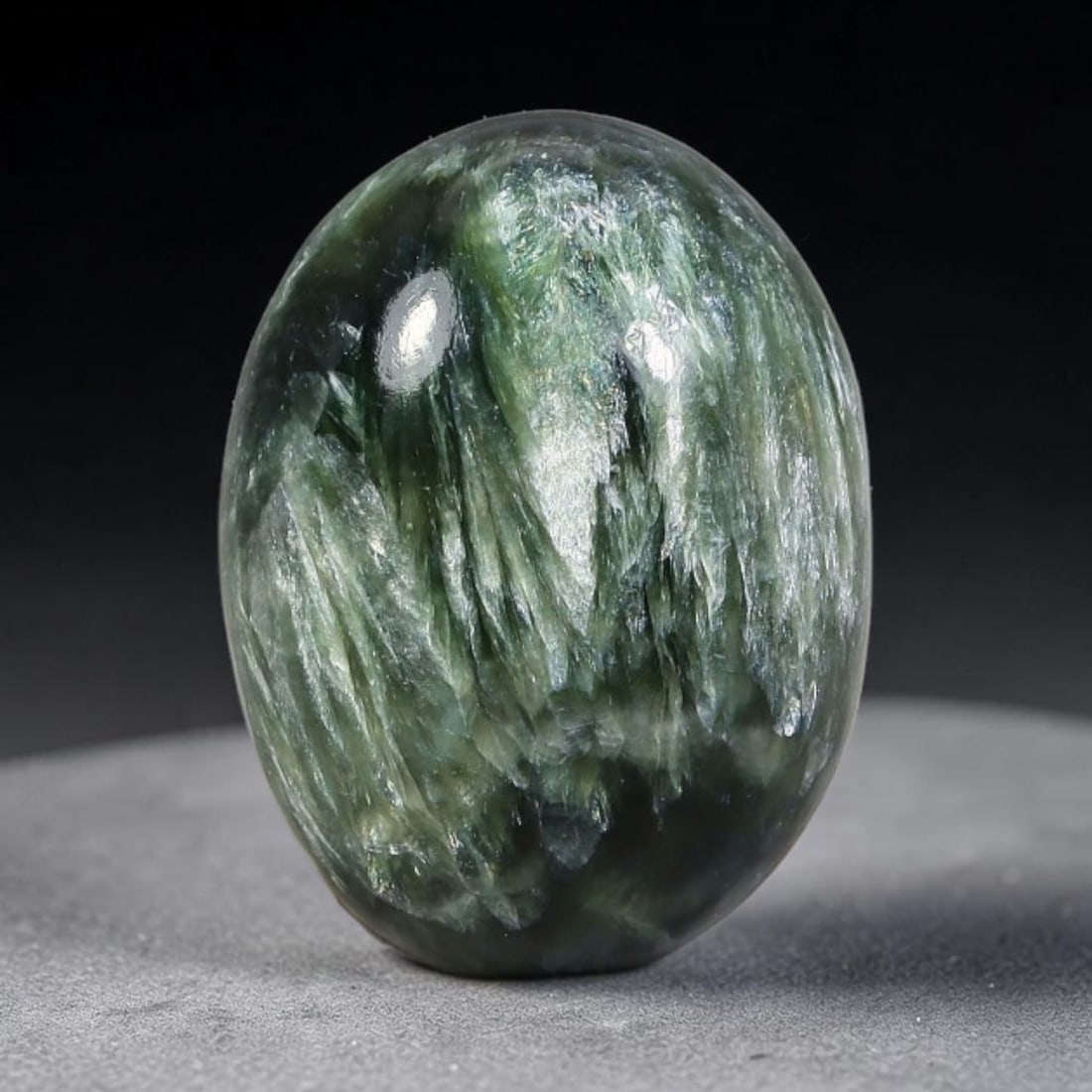 12.07 Carats Natural Deep Green Siberian Seraphinite Polished Cabochon, 98WW: This is a fully natural polished seraphinite specimen sourced from Siberian deposits, displaying distinct feathery fibrous inclusions that create beautiful flowing chatoyant patterns across its smooth