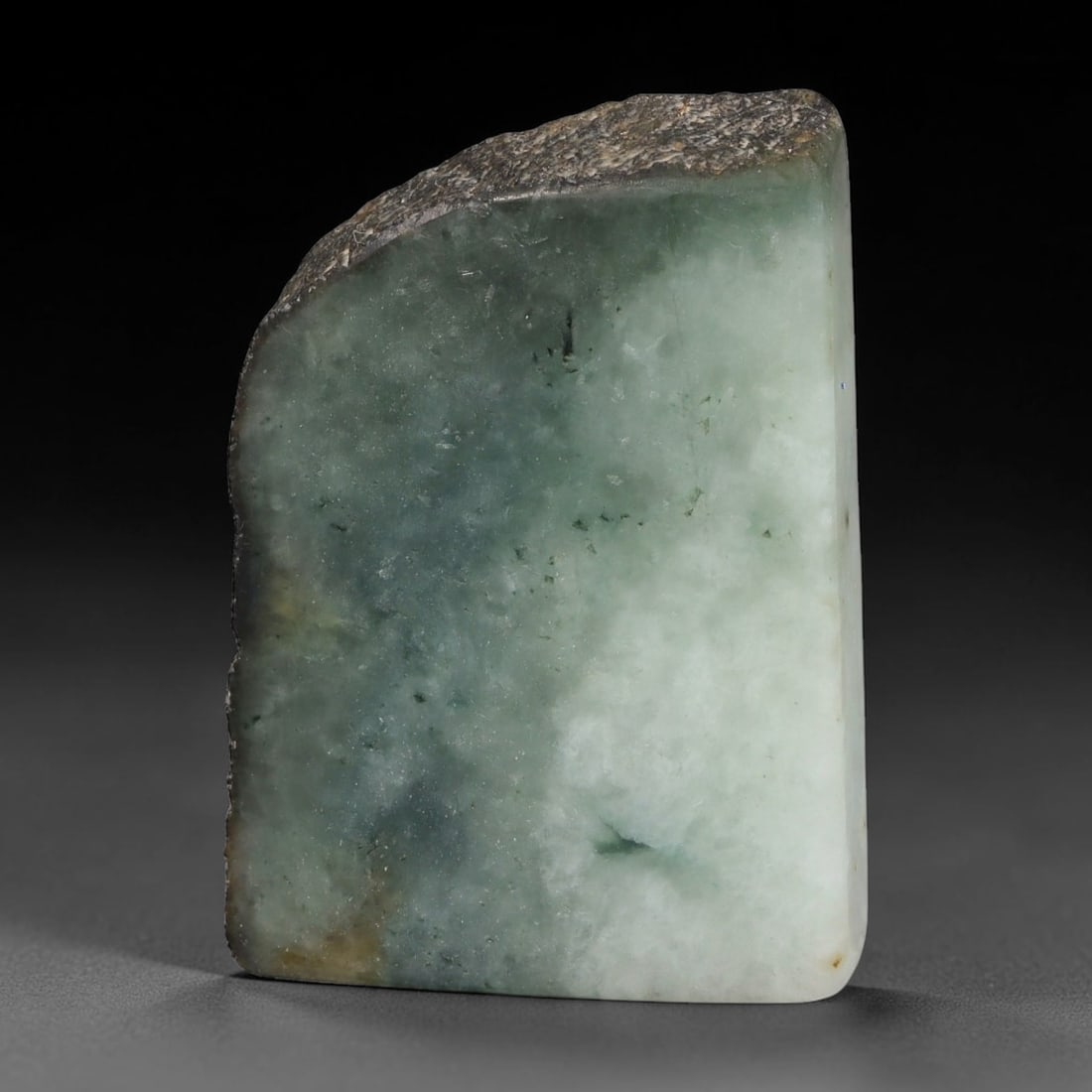 243ct Natural Type A Burmese Jadeite Jade Sliced Rough, 45YR: This specimen is a sliced rough block of natural Type A Burmese jadeite jade. The interior displays natural colour zoning with visible mineral veining and crystalline patterns typical of unprocessed j