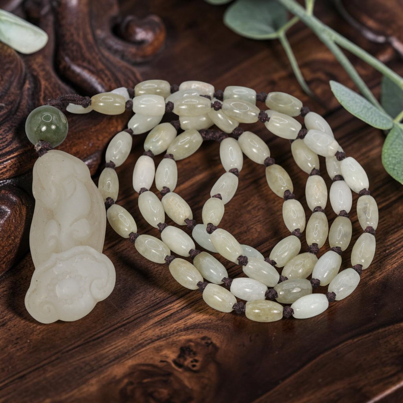 Burmese Jadeite Beaded Necklace with Natural Chinese Jade Ruyi Pendant, 92YJ: This necklace features a hand-carved natural Chinese jade ruyi pendant paired with natural Burmese jadeite pebble beads, strung on a brown cord. The pendant is crafted from pale, creamy-white jade, de