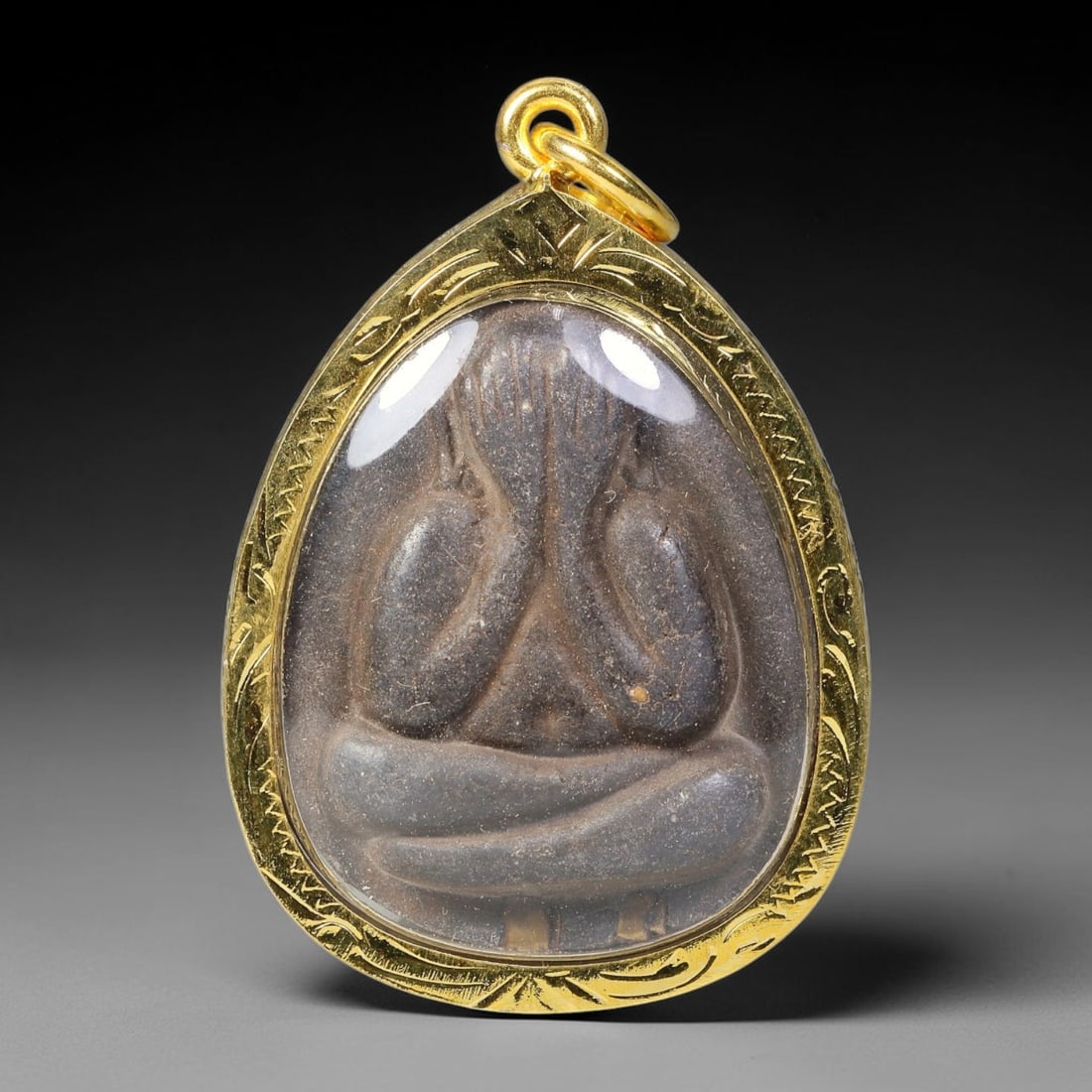 Thai Phra Pidta Closed Eyes Buddha Dual-Sided Gold Plated Metal Casing Amulet, 36YY: Classic teardrop-shaped Phra Pidta Thai amulet with dark sacred clay core sealed under clear transparent cover, fitted inside hand-engraved gold-plated metal casing with matching gold-toned metal loop