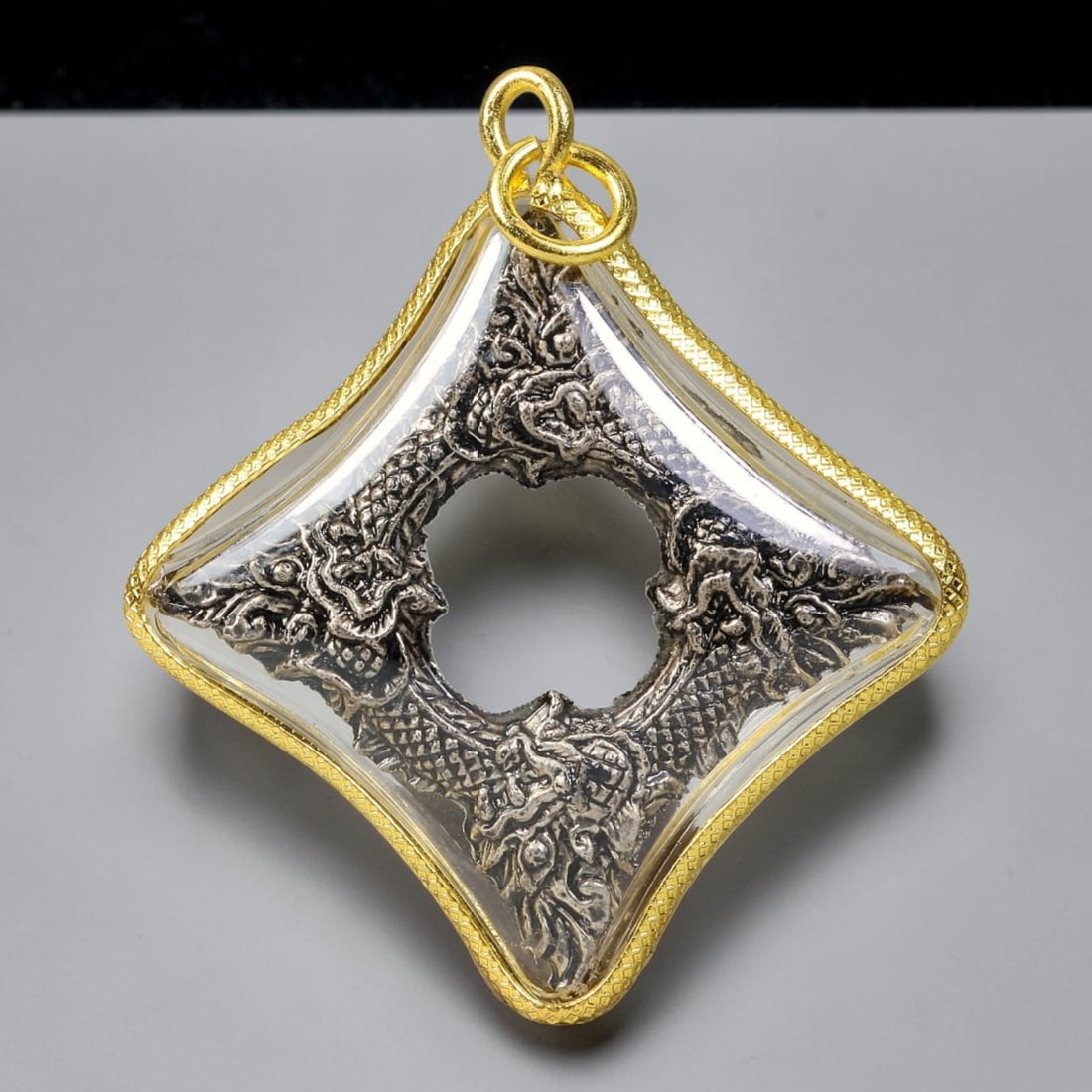 Thai Diamond Shape Gold Frame Four Naga Serpent Ring Amulet Pendant With Clear Casing, 64YY: Curved diamond-shaped textured gold plated amulet measuring 5.0x4.0cm, fitted with dual gold jump rings for easy necklace attachment. Sealed transparent protective cover encloses a hollow center metal