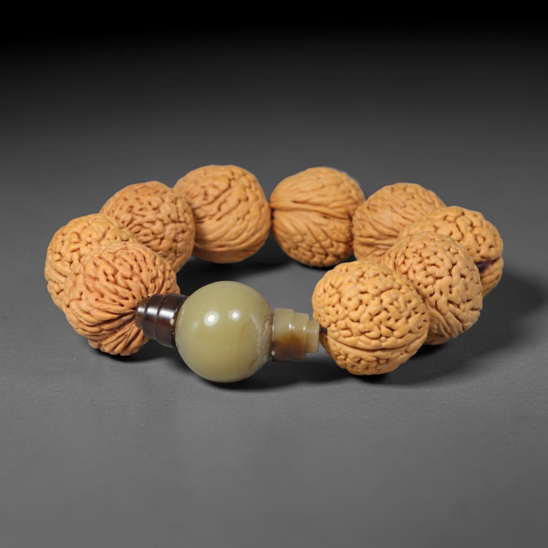 Rudraksha Seed Bracelet - Carved Buddhist Prayer Bead Strand, 62YM: This strand is constructed from naturally textured rudraksha seed beads, shaped into uniform barrel forms with intricate organic fissuring across each surface. The seeds display a consistent pale tan 