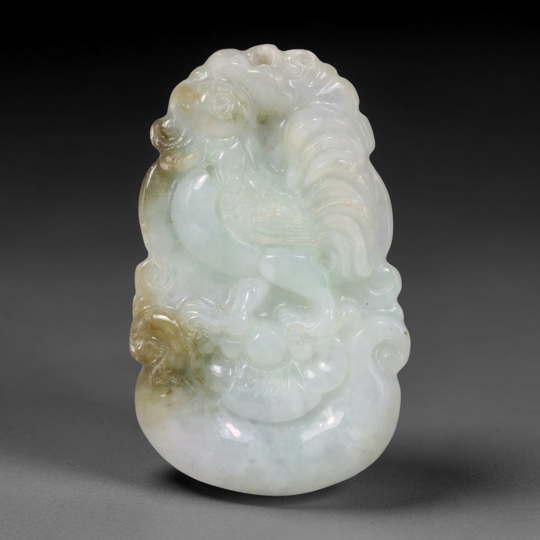 Natural Burmese Type A Jadeite Jade Carved Rooster Pendant, 88XZ: Relief carved pendant crafted from untreated natural Burmese Type A jadeite, exhibiting pale milky celadon green tones with natural amber-brown mineral staining concentrated along the lower left edge.