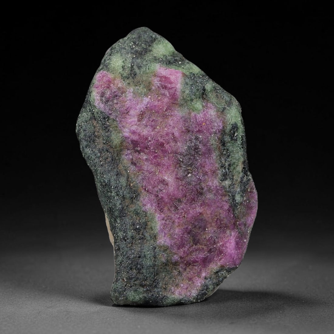 81ct Natural Tanzanian Ruby Zoisite Raw Rough Specimen Mineral Stone, 18YQ: This unpolished mineral rough is natural ruby zoisite sourced from Tanzania, exhibiting distinct banded mineral segregation of vibrant green zoisite, magenta ruby crystals, and dark hornblende inclusi