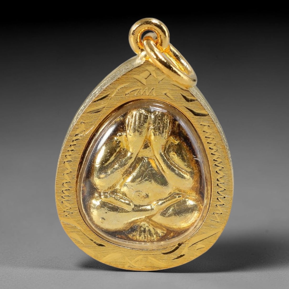 Thai Teardrop Phra Pidta Dual-Sided Gold Plated Metal Casing Amulet, 51YY: Teardrop-shaped Thai Phra Pidta closed-eye Buddha amulet wrapped in intricately engraved golden frame with transparent protective cover. The front features a polished gold relief of seated Phra Pidta 