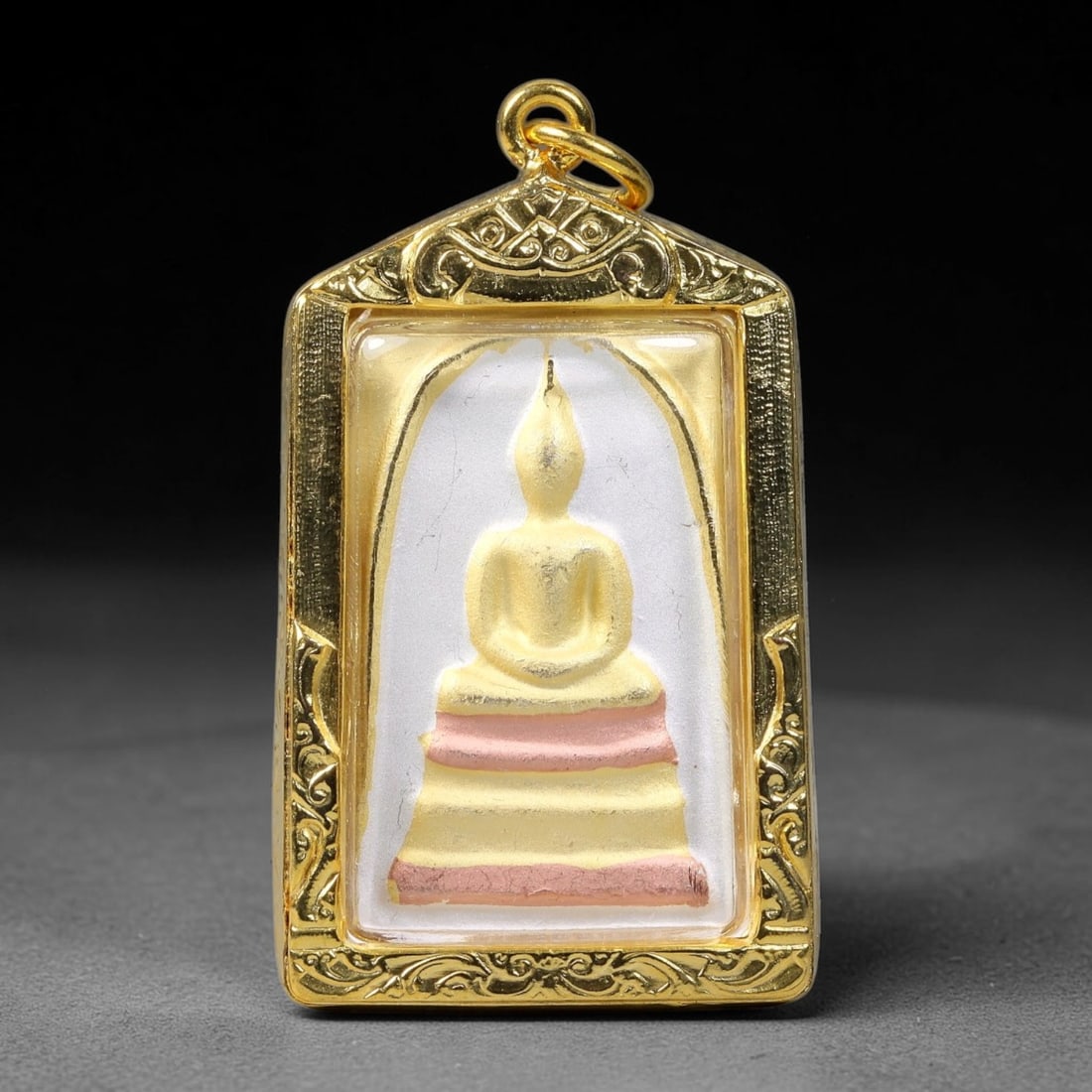 Thai Colored Buddha Votive Amulet - Gold Cased Pendant, 15YY: Hand-finished devotional tablet with smooth seated Buddha relief rendered in soft gold tone, layered stepped base accented with pale pink pigment against an off-white background, framed by subtle mold