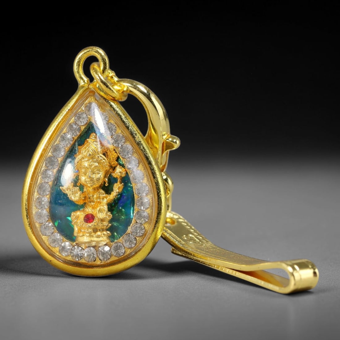 Teardrop Four-Faced God Thai Amulet Pendant with Engraved Gold Clip, 23YY: Teardrop shaped Thai Phra Phrom four-faced deity amulet set within polished gold frame lined with round clear rhinestones. The front features a miniature golden four-faced god figurine set against shi