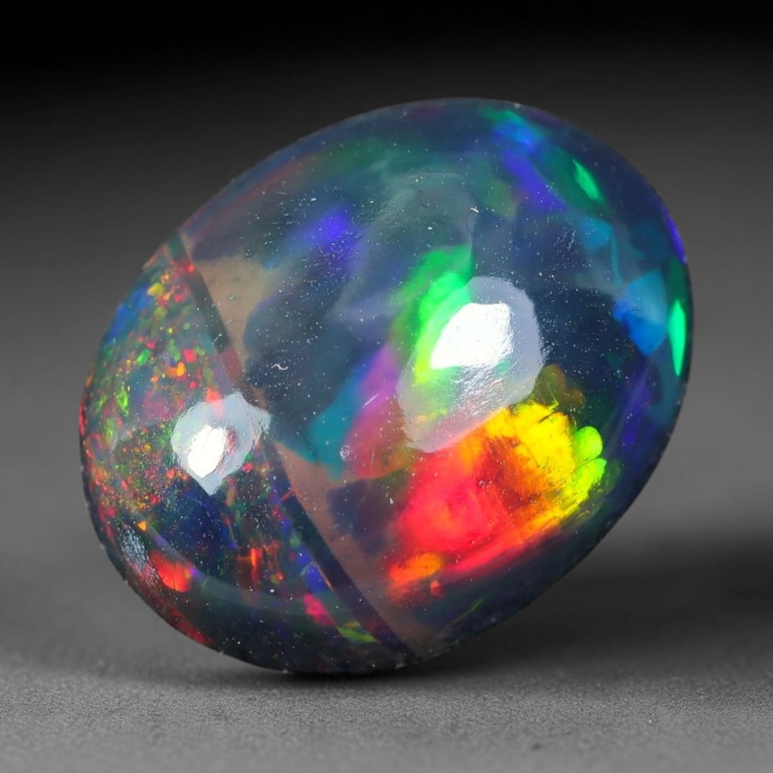 2.69ct Natural Ethiopian Welo Black Smoked Opal Cabochon Loose Gemstone, 75TG: This fully polished Ethiopian Welo opal features a dark smoked base with vivid, sweeping play-of-color shifting across its glossy dome surface, measured at 11.9x9.6x5.0mm. The black smoke treatment de