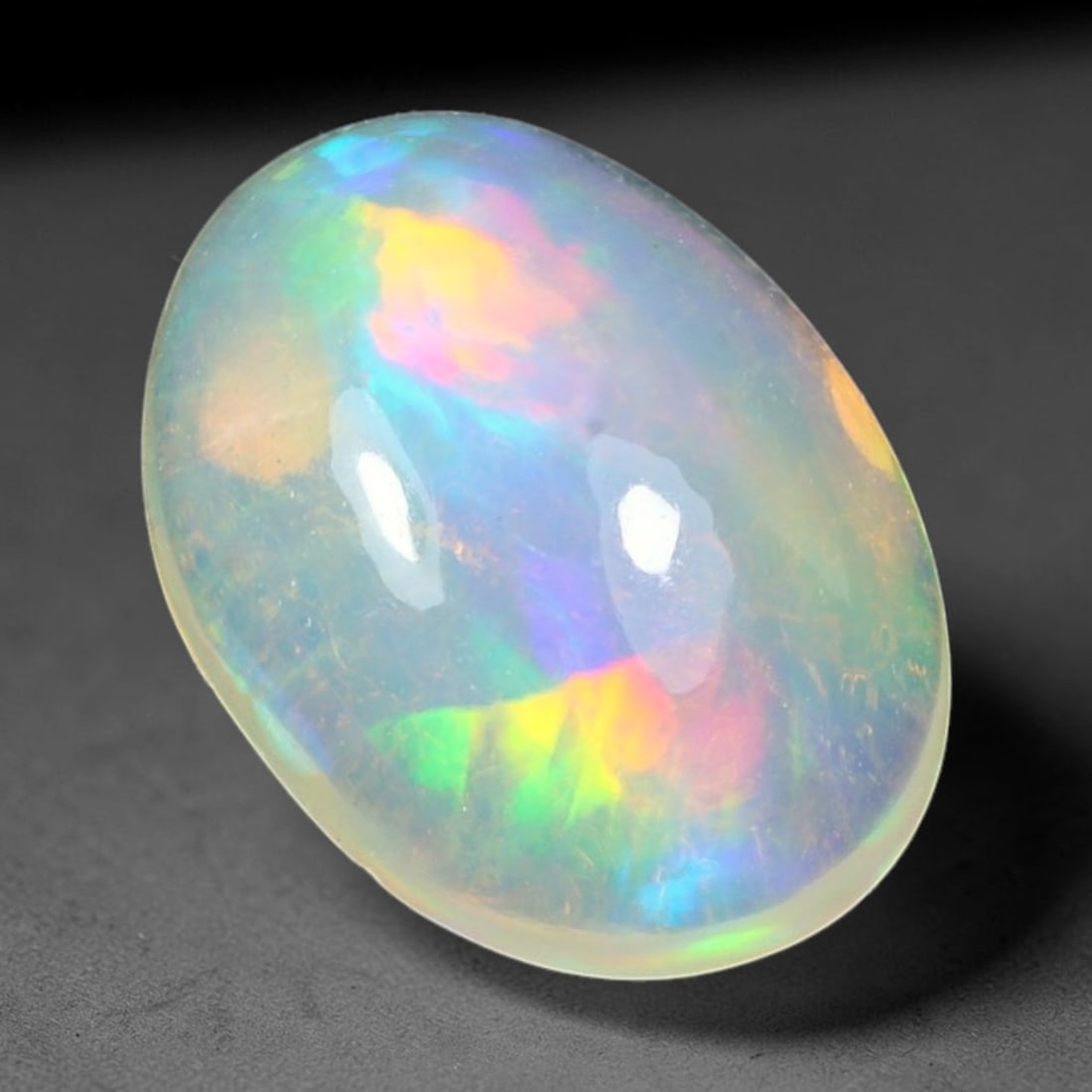 1.97ct Natural Ethiopian Welo Solid Opal Oval Cabochon Loose Gemstone, 65TG: Solid opal cabochon mined from Ethiopia's Welo opal deposits, polished into a smooth elongated oval dome with high reflective gloss. The translucent pale milky base hosts broad shifting play-of-color 