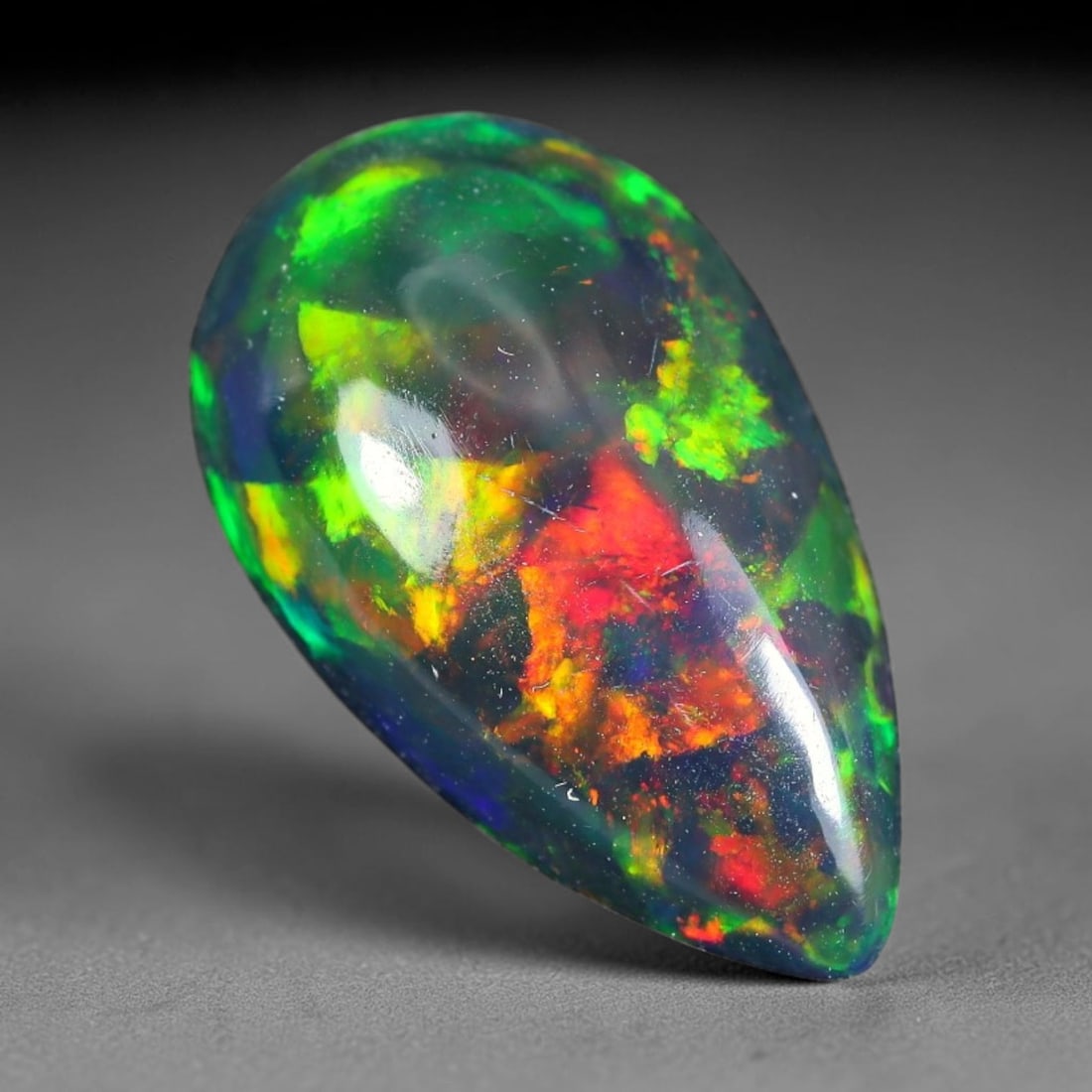2.16ct Natural Ethiopian Welo Black Smoked Opal Cabochon Loose Gemstone, 85TG: This fully polished Ethiopian Welo opal features a dark smoked base with vivid, sweeping play-of-color shifting across its glossy dome surface, measured at 14.2x8.3x4.5mm. The black smoke treatment de