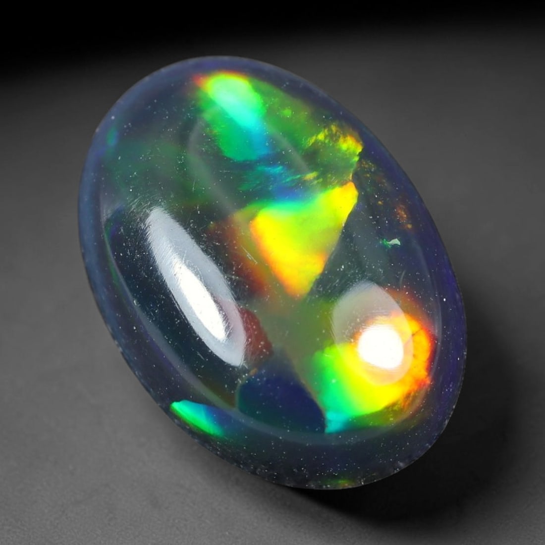 2.50ct Natural Ethiopian Welo Black Smoked Opal Cabochon Loose Gemstone, 73TG: This fully polished Ethiopian Welo opal features a dark smoked base with vivid, sweeping play-of-color shifting across its glossy dome surface, measured at 12.1x8.5x4.7mm. The black smoke treatment de