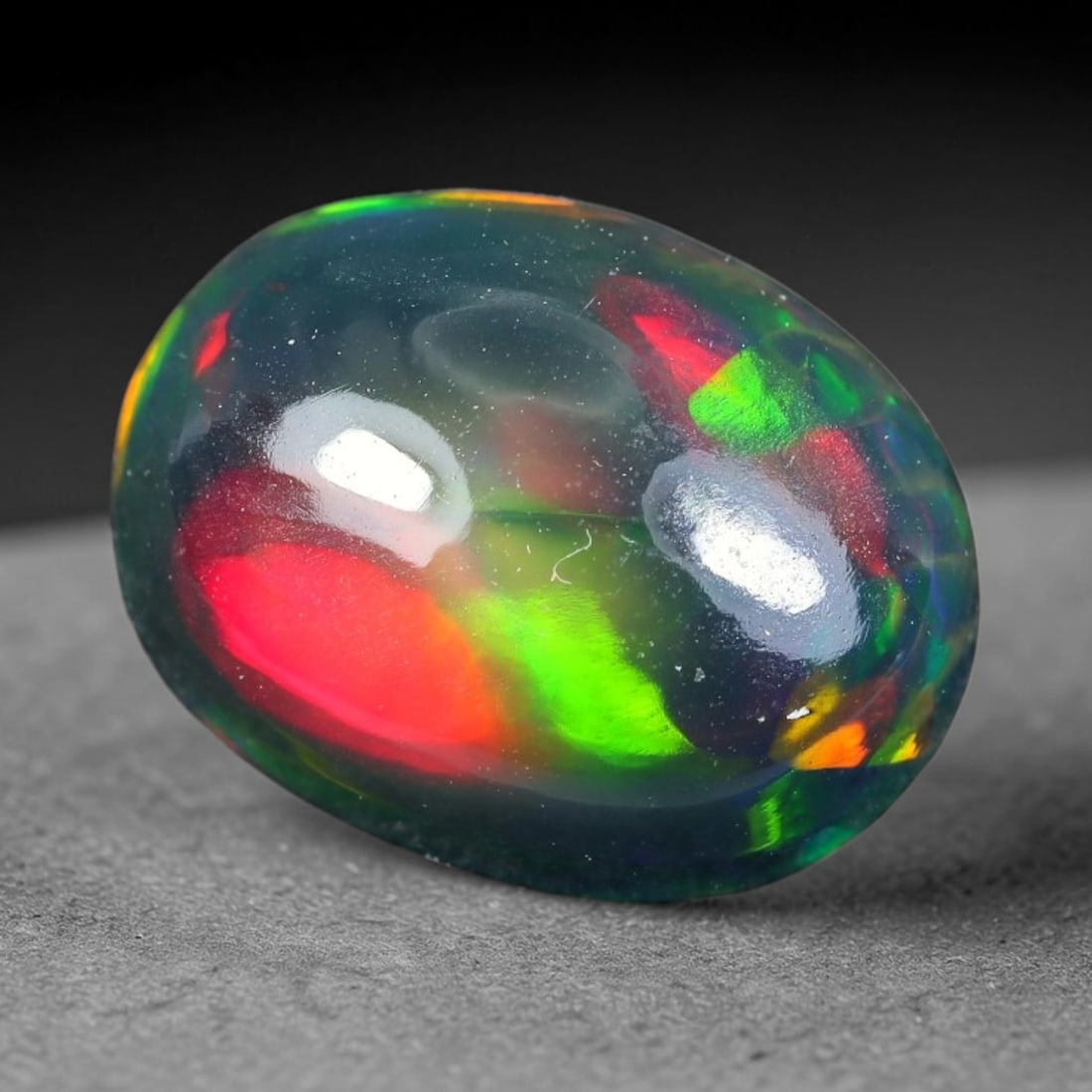 2.49ct Natural Ethiopian Welo Black Smoked Opal Cabochon Loose Gemstone, 82TG: This fully polished Ethiopian Welo opal features a dark smoked base with vivid, sweeping play-of-color shifting across its glossy dome surface, measured at 11.4x8.6x5.1mm. The black smoke treatment de