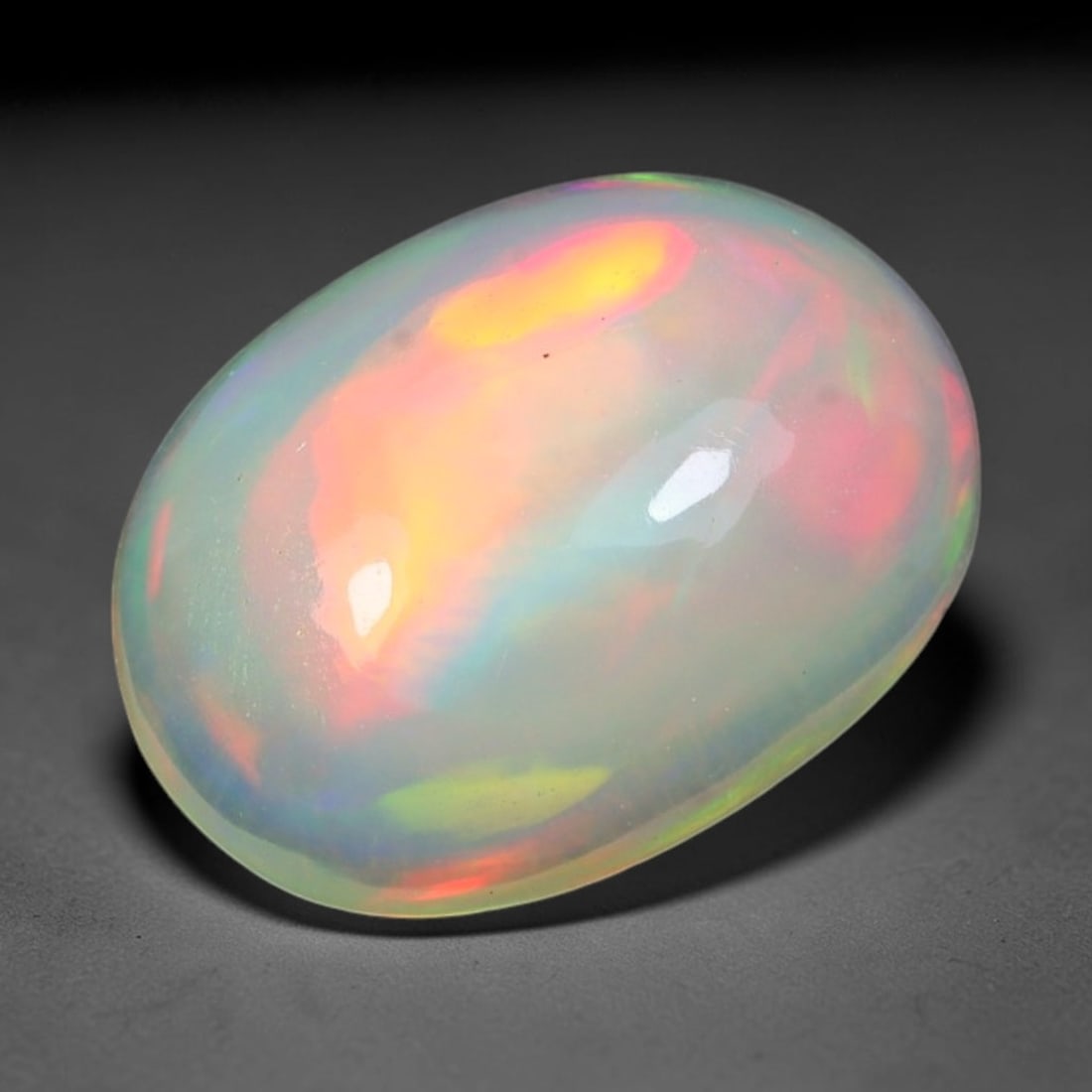 2.01ct Natural Ethiopian Welo Solid Opal Oval Cabochon Loose Gemstone, 49TG: Solid opal cabochon mined from Ethiopia's Welo opal deposits, polished into a smooth elongated oval dome with high reflective gloss. The translucent pale milky base hosts broad shifting play-of-color 