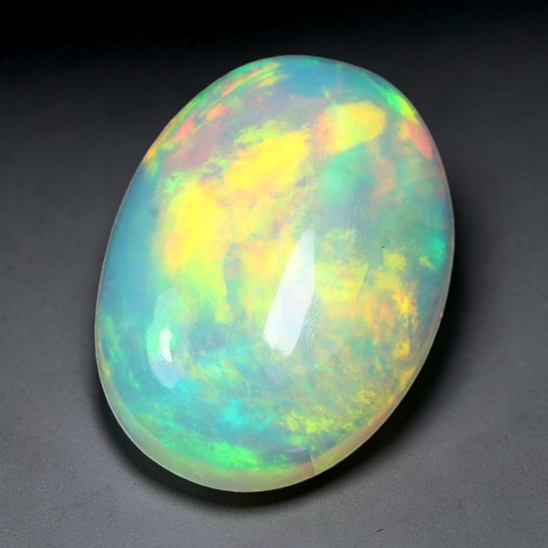 1.46ct Natural Ethiopian Welo Solid Opal Oval Cabochon Loose Gemstone, 42TG: Solid opal cabochon mined from Ethiopia's Welo opal deposits, polished into a smooth elongated oval dome with high reflective gloss. The translucent pale milky base hosts broad shifting play-of-color 