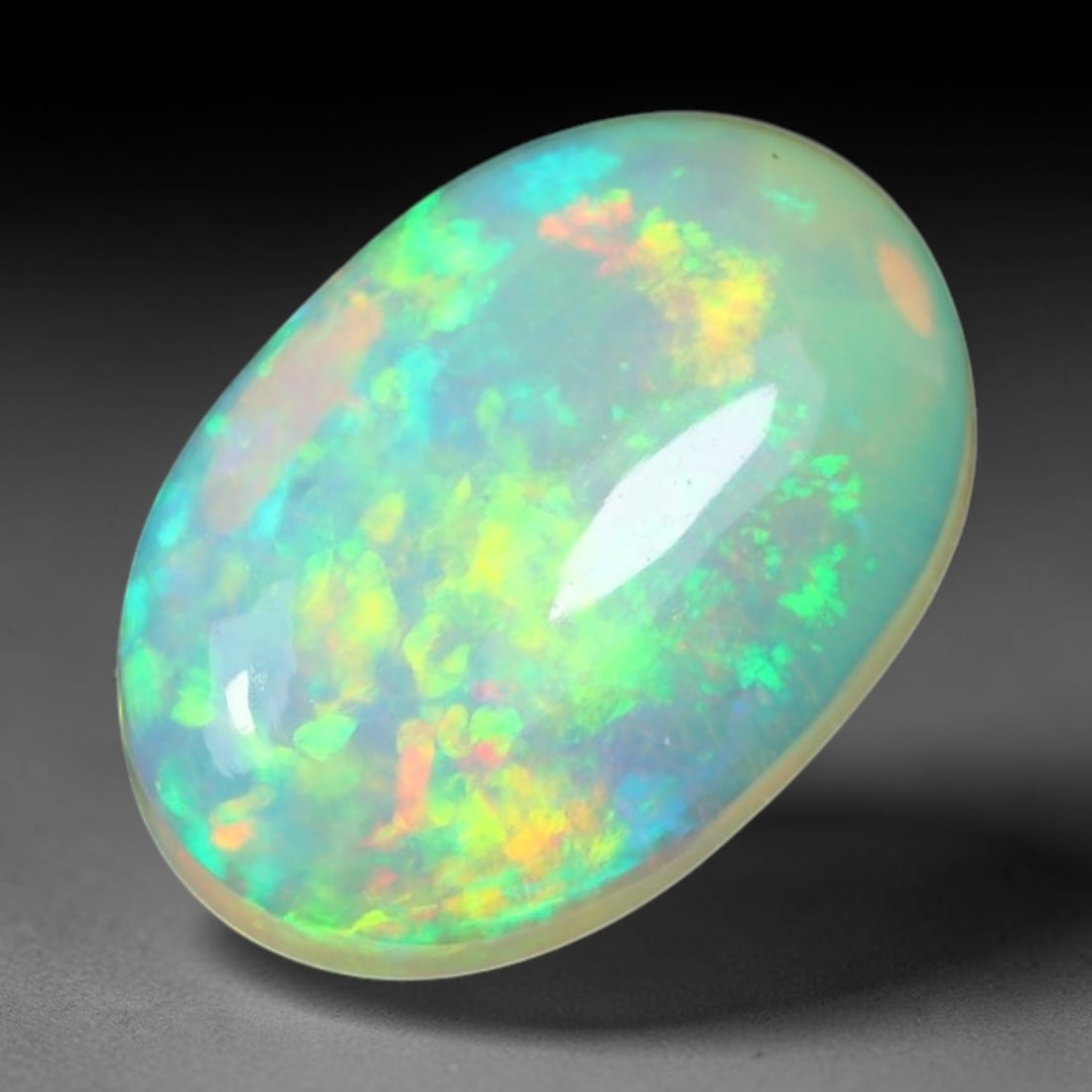 1.50ct Natural Ethiopian Welo Solid Opal Oval Cabochon Loose Gemstone, 57TG: Solid opal cabochon mined from Ethiopia's Welo opal deposits, polished into a smooth elongated oval dome with high reflective gloss. The translucent pale milky base hosts broad shifting play-of-color 
