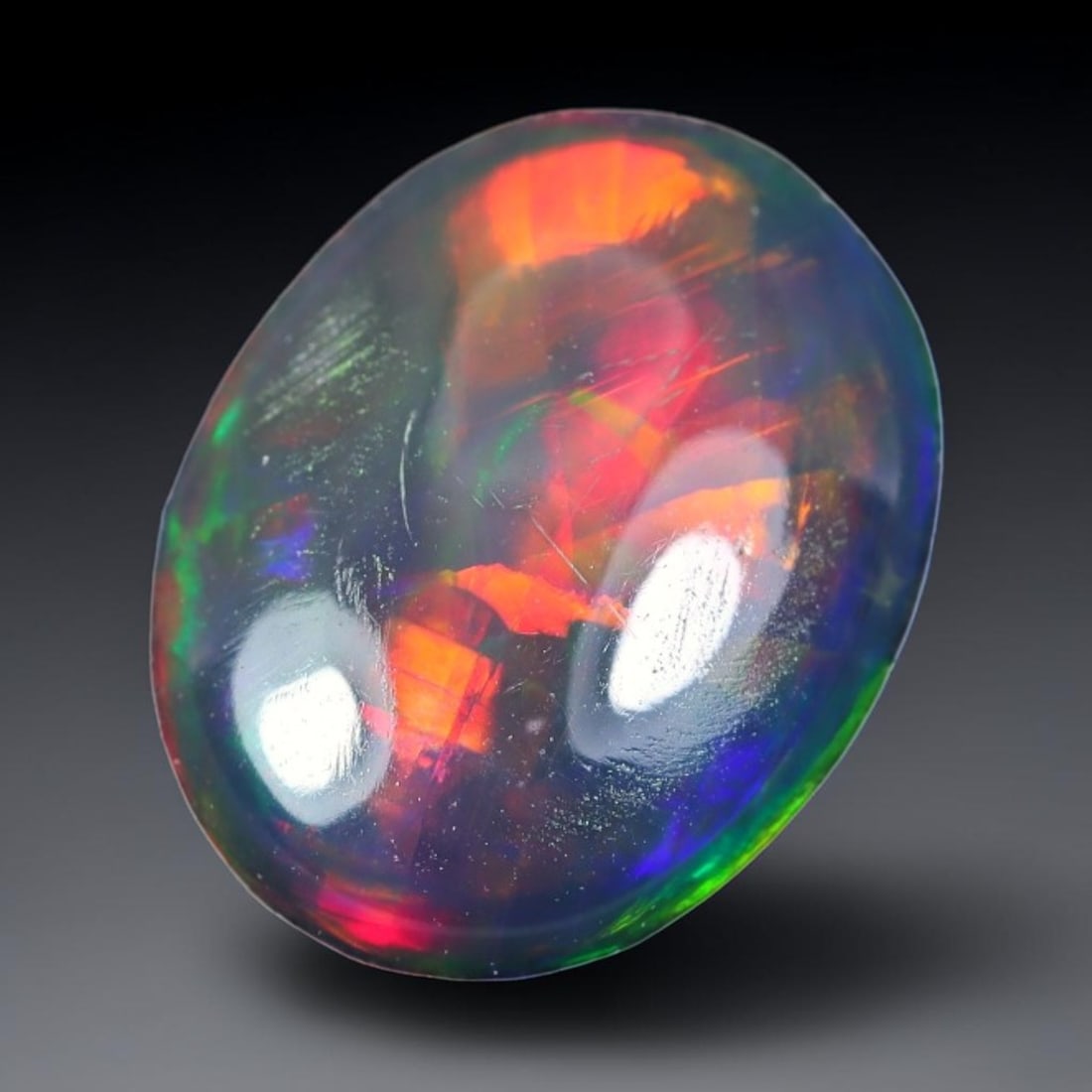 1.28ct Natural Ethiopian Welo Black Smoked Opal Cabochon Loose Gemstone, 77TG: This fully polished Ethiopian Welo opal features a dark smoked base with vivid, sweeping play-of-color shifting across its glossy dome surface, measured at 10.9x8.4x3.1mm. The black smoke treatment de