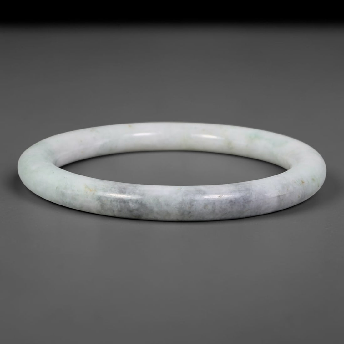 Natural Burmese Type A Pale Cloudy Grey Floating Green Jadeite Jade Bangle Bracelet, 66TD: Polished from natural Burmese jadeite, this slender round bangle displays a milky pale white base softened by cloudy grey clouding and faint wisps of floating green across the matrix. Crafted in a del