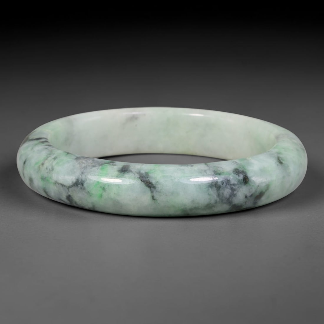 Natural Burmese Type A Moss Cloud Floating Green Jadeite Jade Bangle Bracelet, 67TD: Polished from natural Burmese jadeite, this solid bangle features a pale milky base overlaid with swirling mossy green and dark grey clouded veining across the matrix. Formed in a traditional rounded 